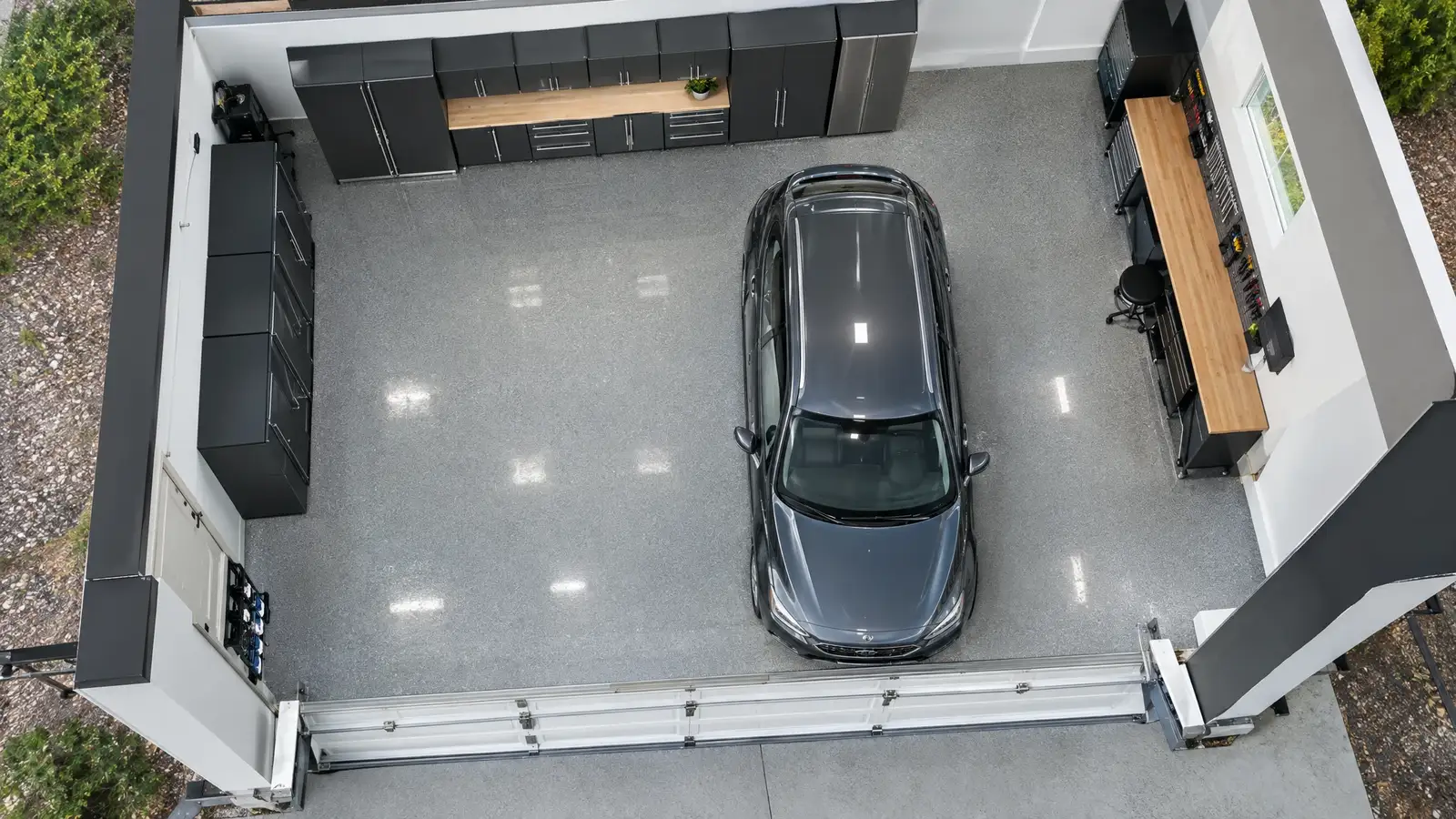 A finished custom garage with cabinets, slatwall and a glossy floor